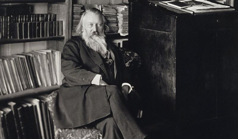 A man with a beard sits cross-legged and looks directly ahead of him