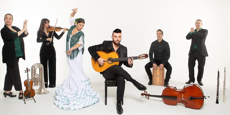 Flamenco musicians and dancers stood in front of a white background with their instruments. 