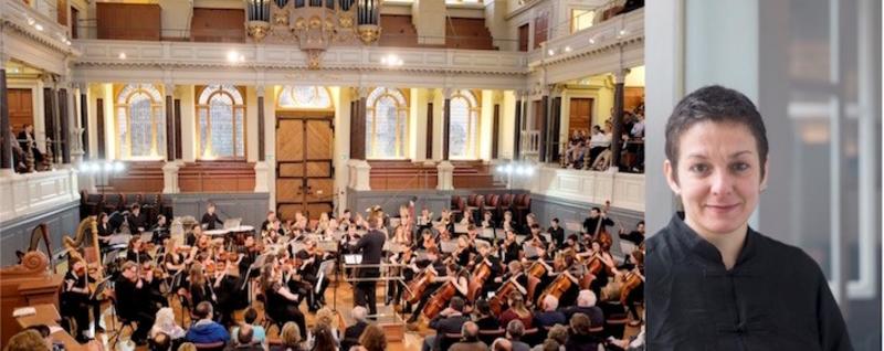 Orchestra playing in the main hall with a portrait of Conductor