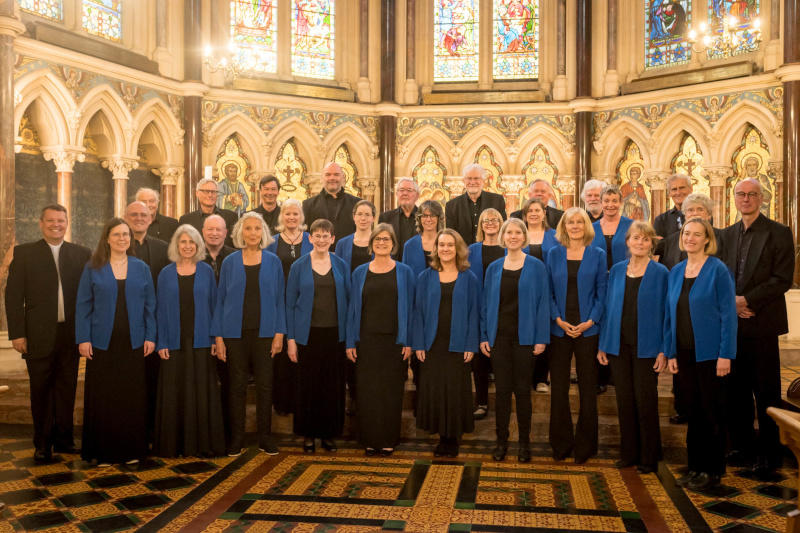 A picture of Oxford Pro Musica singers at an alter dressed in blue
