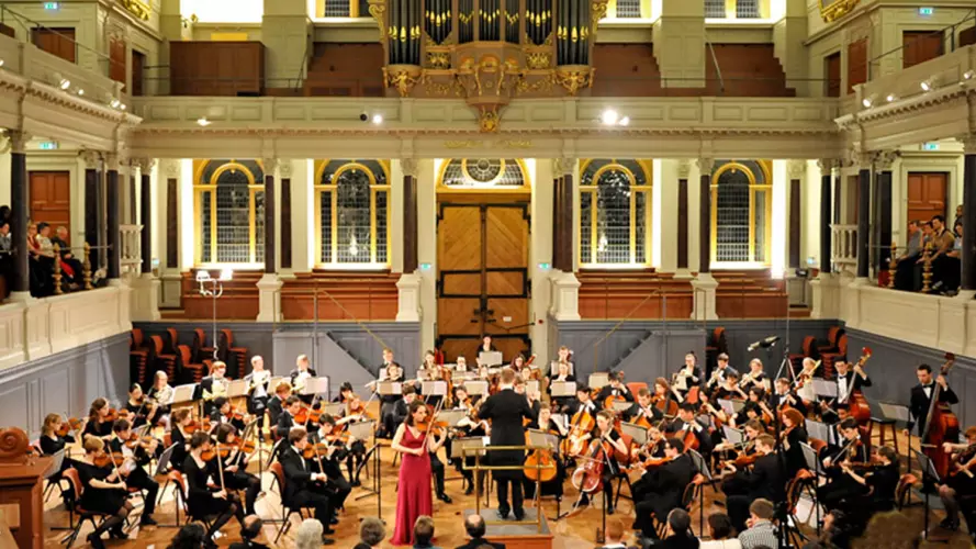 Photo of full orchestra with violin soloist performing a concert in the Sheldonian Theatre