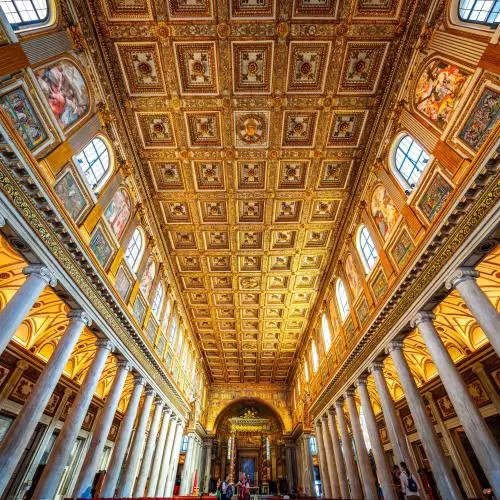 view looking up of an ornate golden ceiling with with columns running down to the floor
